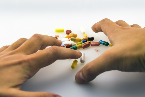 Zwei Hände greifen nach verschiedenenfarbigen Tabletten. Foto: Emilian Danaila (Pixabay)